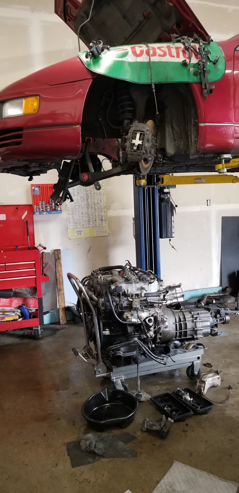 A car up on our lift with the engine and gearbox out on the floor below it